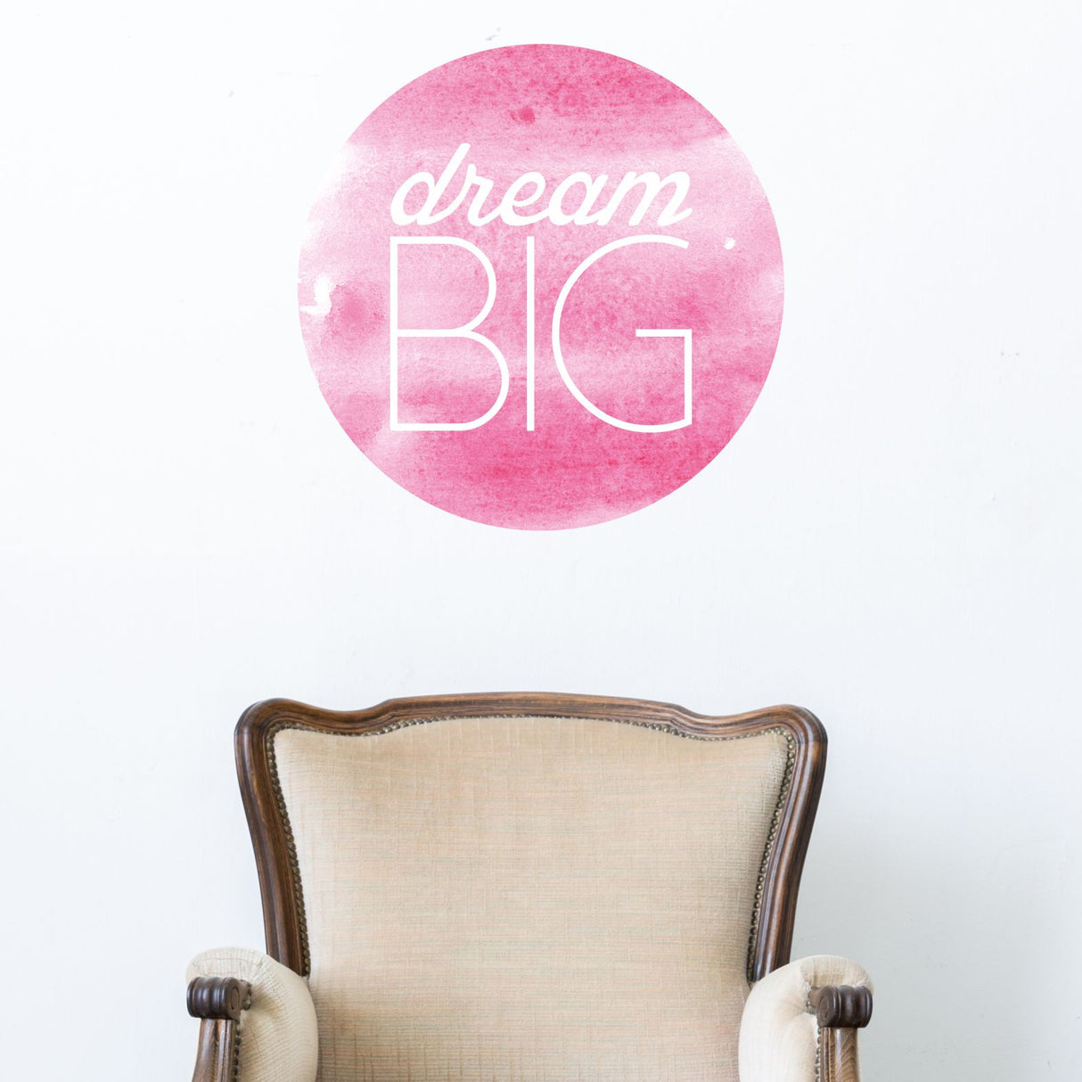Decorative wall sticker with 'dream BIG' text on a pink watercolor circle above an armchair.