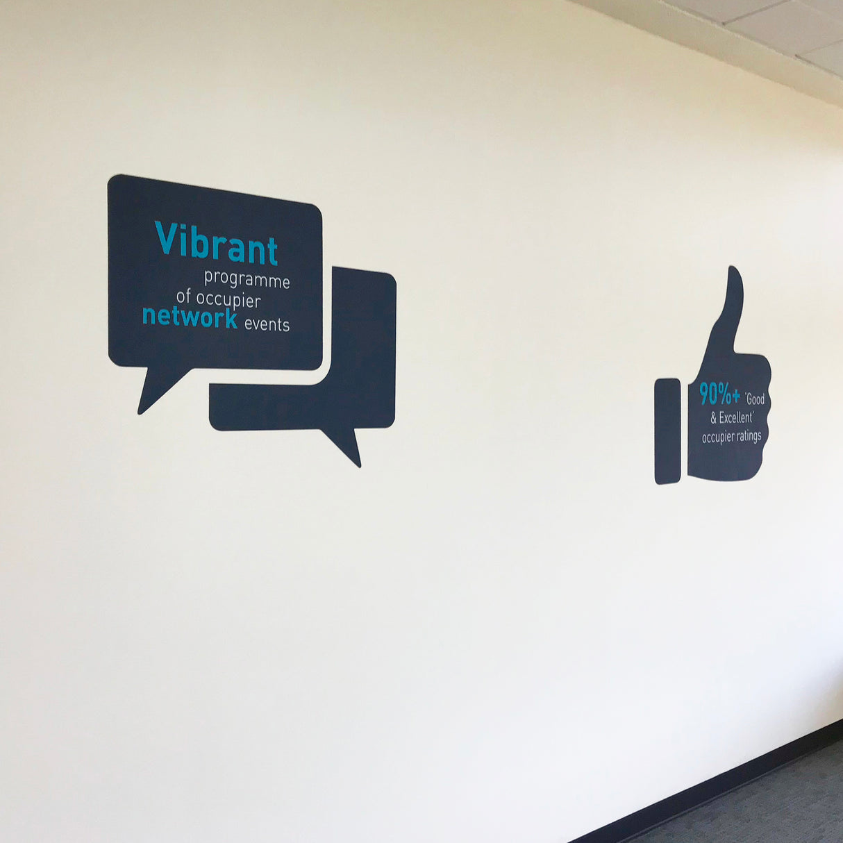 Decorative wall decal with speech bubbles and a thumbs-up icon on a white wall.