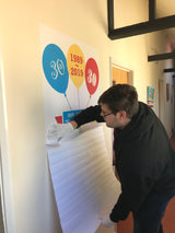 Person sticking colorful balloons poster on a wall