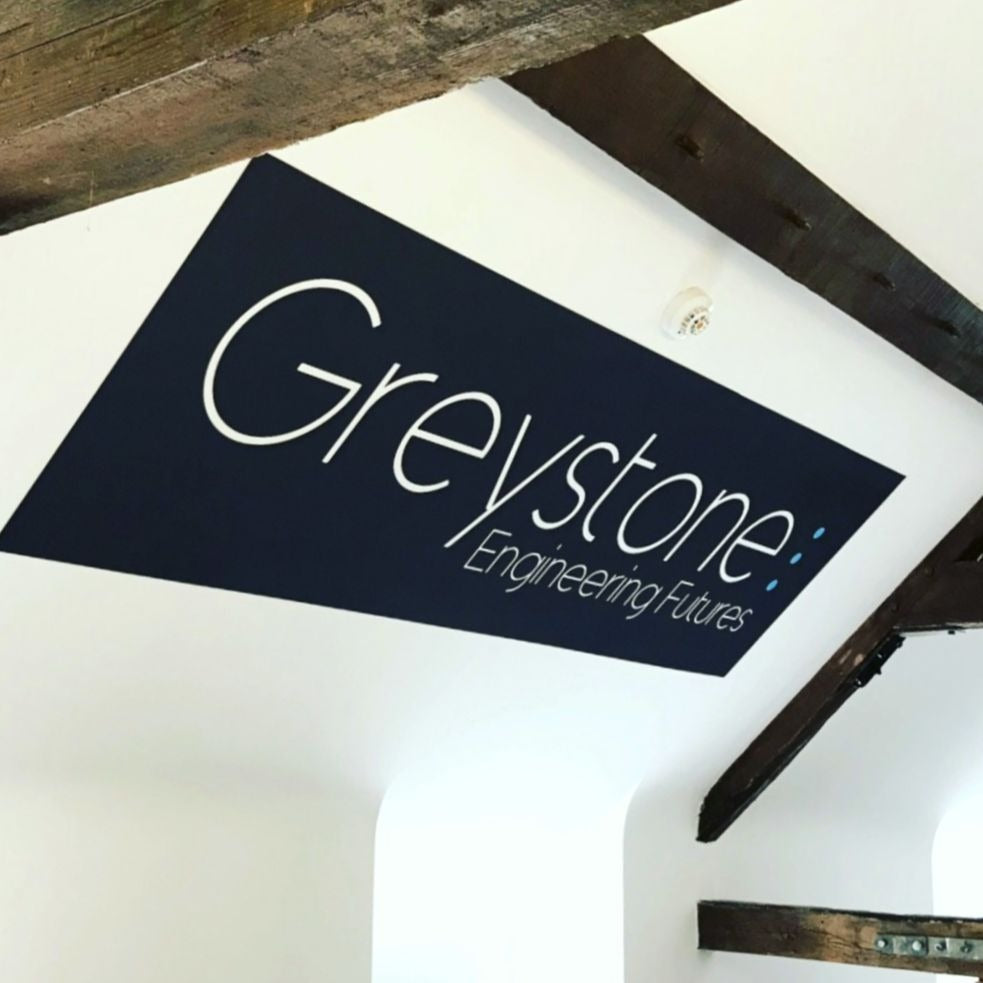 Greystone Engineering Futures logo on a white wall with wooden beams.
