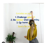 Person sticking motivational quotes on a wall with a plant beside them.