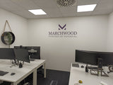 Modern office setup with desks, computers, and Marchwood logo on the wall.