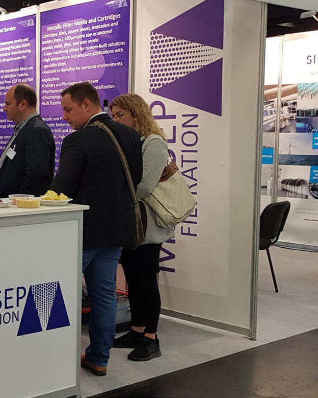 People interacting at a trade show booth with a prominent display of text and branding.