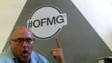 Man pointing at a '#OFMG' logo on a wall
