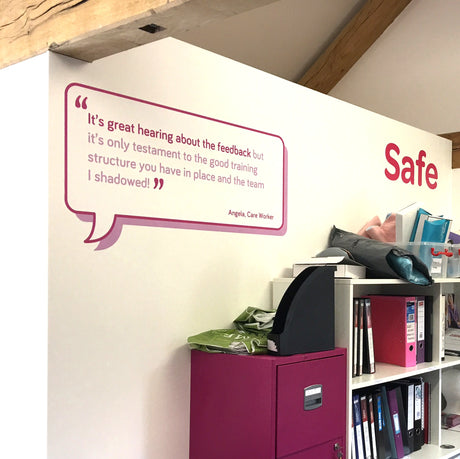 Wall with a quote sticker and a purple filing cabinet in an office setting