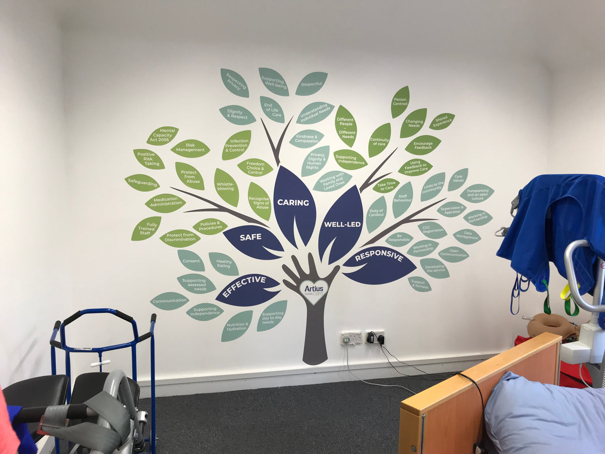 Wall mural of a tree with branches and leaves on a white wall in a room with medical equipment.