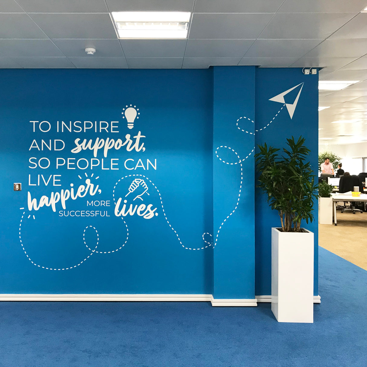 Blue wall with motivational quote and decorative elements in an office setting
