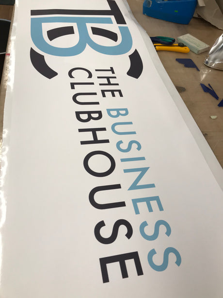 Logo of 'The Business Clubhouse' on a white background with tools in the background.