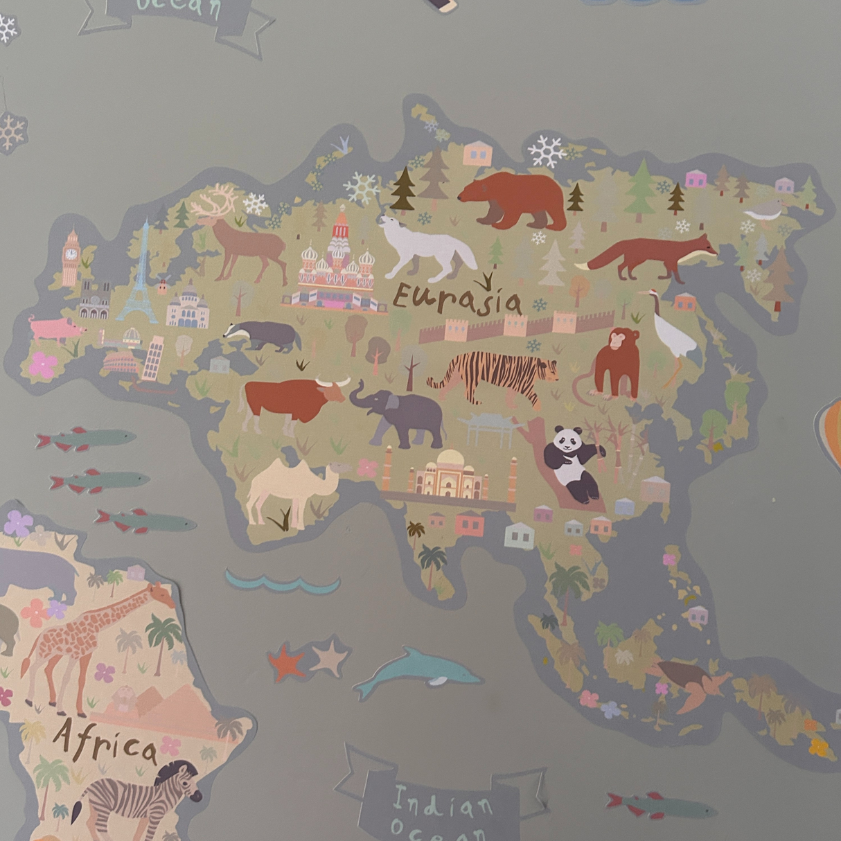 Children's world map with illustrations of animals and continents on a gray background