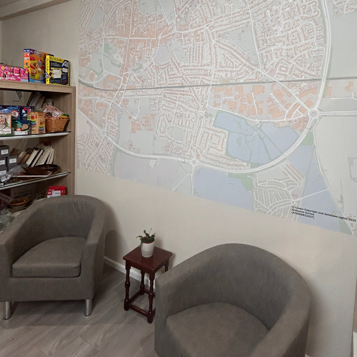 Two gray chairs in a room with a large wall map and a bookshelf.