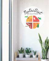 NutriDiet logo with fruits on a white wall above a shelf with plants.