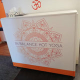 White counter with 'In Balance Hot Yoga' design and Om symbol in the background