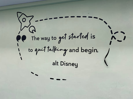 Motivational quote on a whiteboard with a rocket and speech bubble design, featuring 'alt Disney' text.