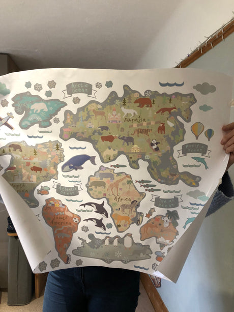 Person holding a large world map with animal illustrations