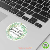 Round sticker with green wreath design on a laptop keyboard